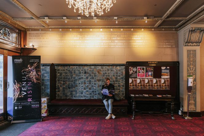 A woman reading in the foyer at Regent Theatre.